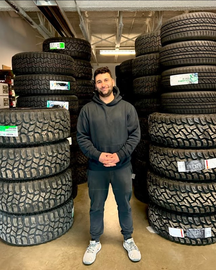 KFWheels owner in the shop surrounded by stacks of off-road tires