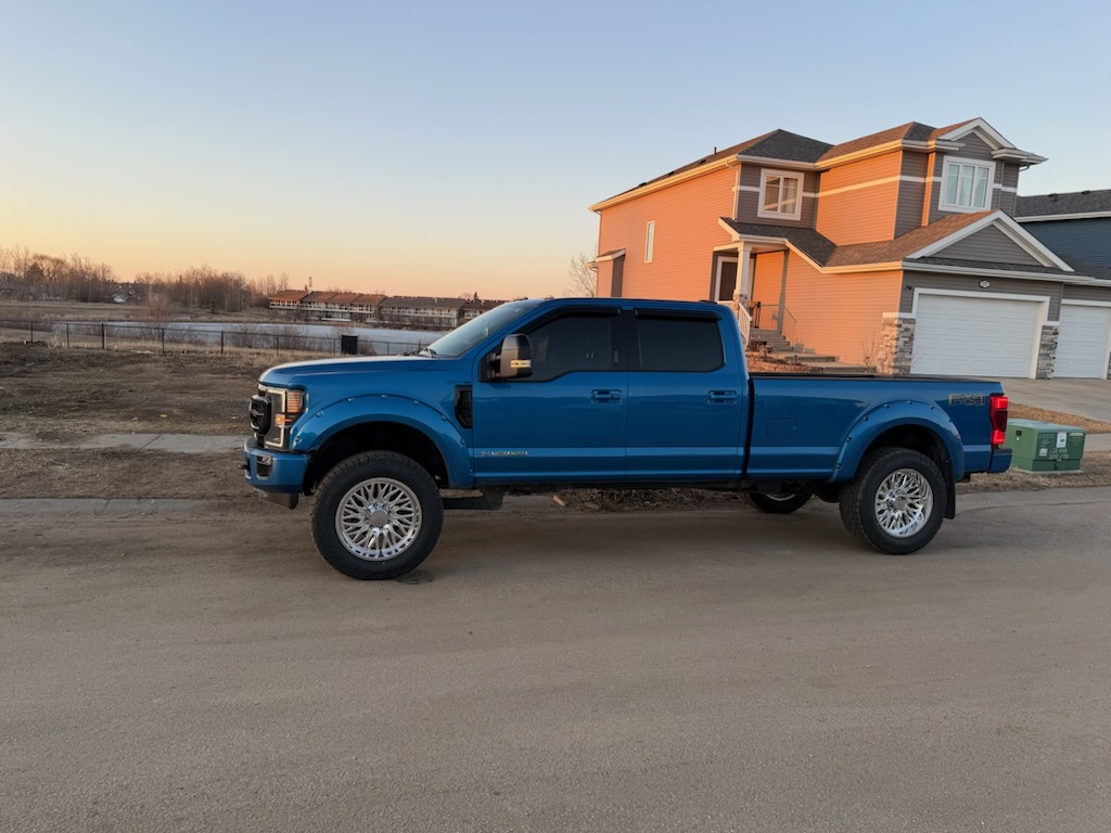 Blue Ford F-350 FX4 on forged wheels at sunset
