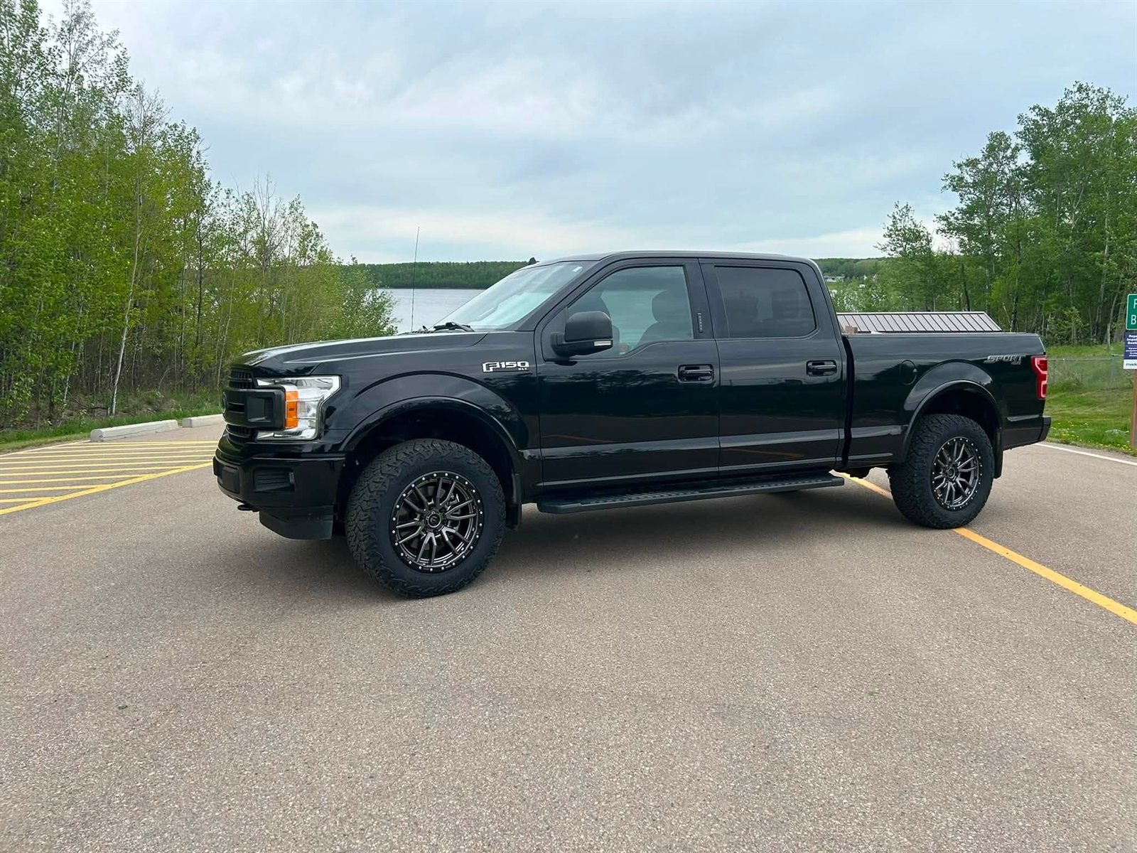 Black Ford F-150 Sport on gunmetal wheels by the lake