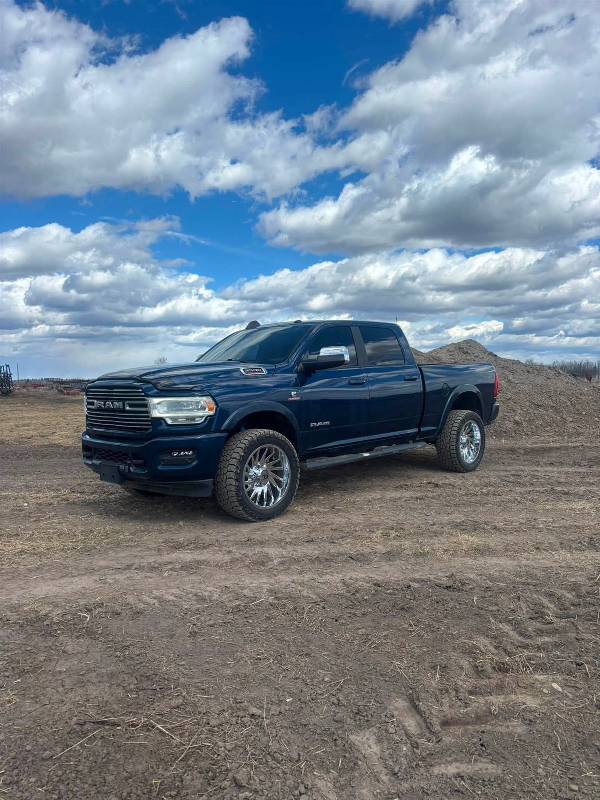 Dark blue Ram 2500 Laramie on chrome forged wheels in the field